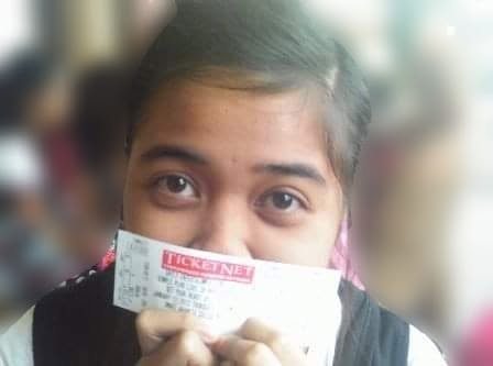 Young Camille holding up a concert ticket