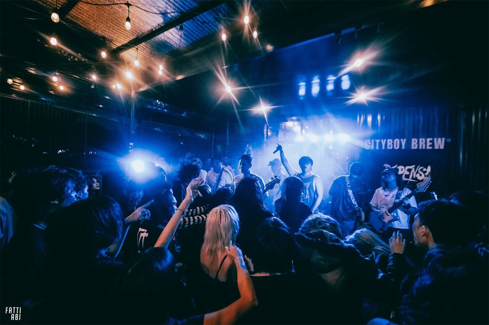 A packed crowd cheering as a band plays at one of our live shows